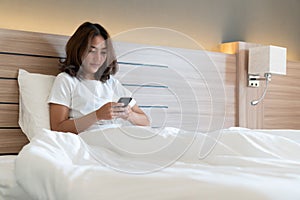 Young woman using smartphone on bed