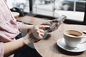 Young woman using smartphone at cafe. Student girl texting on mobile phone at coffee shop. Communication, home work or study