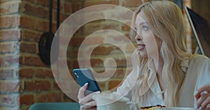 Young Woman Using Smartphone In A Coffeeshop. Caucasian female reading text message on her cell phone in cafe.