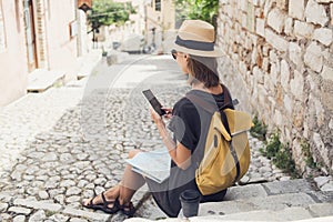 Young woman using smartphone in Corfu old town. Traveler girl looking at mobile phone at italian street.