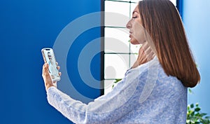 Young woman using smartphone having teleconsultation at home photo