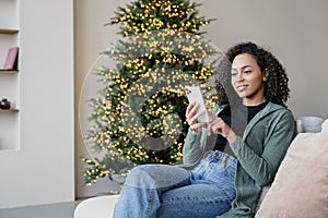 Young woman using smartphone at home during Christmas holiday, Student girl texting on mobile phone