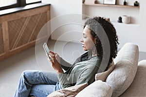 Young woman using smartphone at home. Mixed race girl looking at mobile phone. Communication, social distancing, connection concep