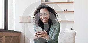 Young woman using smartphone at home. Mixed race girl looking at mobile phone. Communication, social distancing, connection concep