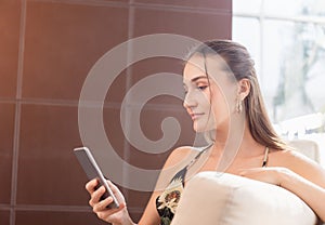 Young woman using smartphone in the hotel lobby, Young attractive businesswoman looking at her cellphone