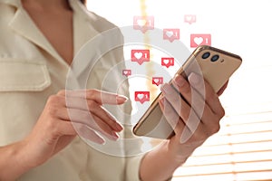 Young woman using smartphone indoors, closeup. Social media