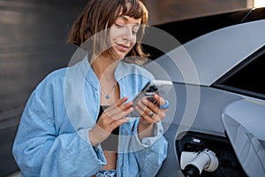 Woman charges her electric car near a house