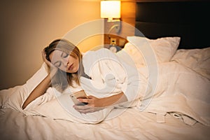 Young woman using smartphone. Lying on bed