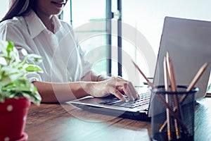 young woman is using smartphone and notebook computer in office