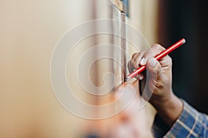 Young woman using a spirit level and marking the wall with a pen