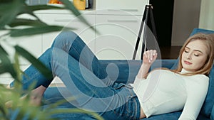 Young woman using tablet computer while sitting on sofa.