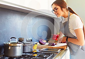 Young woman using a tablet computer to cook in her kitchen