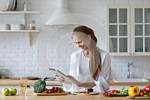 Young woman using a tablet computer to cook in her kitchen at home