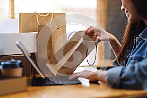 A young woman using tablet pc for online shopping , opening shopping bags and postal parcel box on the table