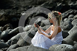Young woman using tablet on rocky beach