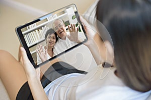A young woman is using tablet to Video calling or Webcam to grandparent ,  telecommunications technology , parenthood family