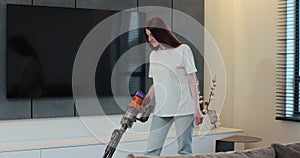 Young woman using vacuum cleaner to clean floor in the living room at home. Cleaning home by using wireless vacuum