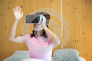 Young woman using virtual reality headset in bed. VR, Future digital technology, game, movies entertainment, metaverse, NFT and 3D