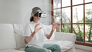 Young woman using virtual reality VR goggle at home for vivancy experience