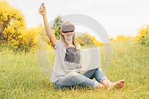 Young woman using VR glasses outdoors in a park