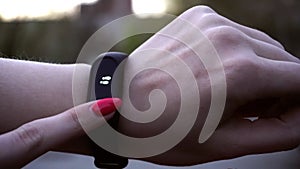 Young woman using wearable fitness tracker. The smart band with display touchpad and heart rate monitor. Entertainment