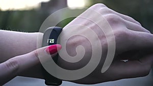 Young woman using wearable fitness tracker. The smart band with display touchpad and heart rate monitor. Entertainment