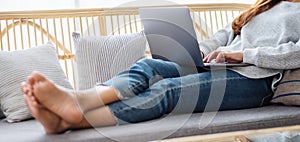 A young woman using and working on laptop computer while lying on a sofa at home