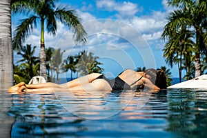 Young woman on vacation at hawaii, sexy girl at the swimming pool. Bikini model at the infinity pool.