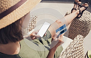 Young woman on vacation using credit card and smart phone with blank empty mockup screen, Online shopping, booking concept