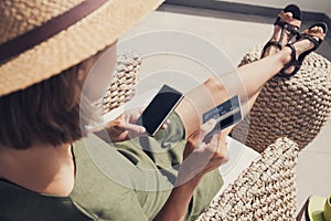 Young woman on vacations using phone and credit card. Online shopping concept