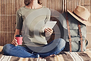 Young woman on vacations using smartphone and drinking coffee. Travel concept