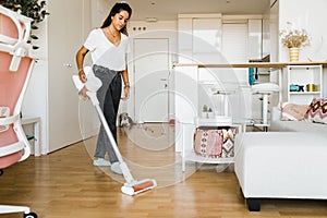 young woman vacuuming her home