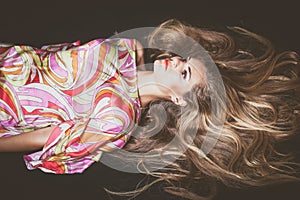 Young woman with very long blonde hair lie down studio shot