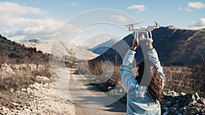 Young woman videographer catching flying aircraft with camera.Controlling landing of drone.Female filmmaker in nature photo