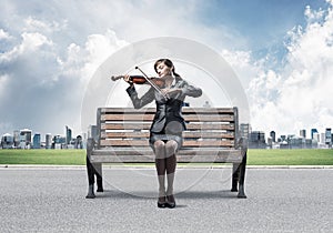 Young woman with violin sitting on wooden bench