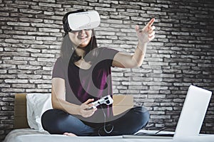 Young woman in virtual reality headset or 3d glasses playing video game and pointing in the air, gaming and technology concept