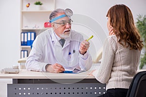 Young woman visiting old male doctor otorhinolaryngologist photo