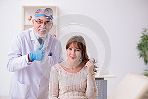 Young woman visiting old male doctor otorhinolaryngologist photo