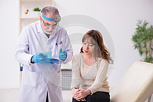 Young woman visiting old male doctor otorhinolaryngologist photo