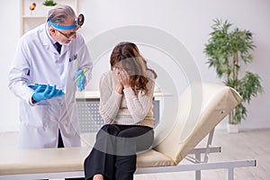Young woman visiting old male doctor otorhinolaryngologist photo