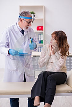 Young woman visiting old male doctor otorhinolaryngologist photo