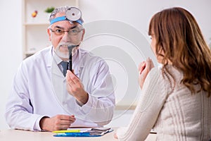 Young woman visiting old male doctor otorhinolaryngologist photo