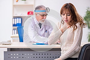 Young woman visiting old male doctor otorhinolaryngologist photo