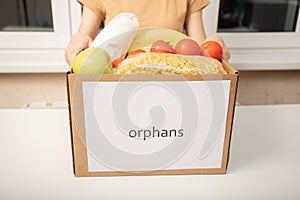 A young woman volunteer with a box of food products for orphans in orphanages photo