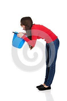 Young woman vomiting to bucket.