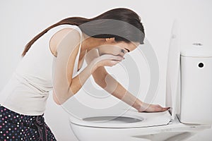 Young woman vomiting into toilet bowl photo