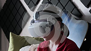 Young Woman in VR Helmet Sitting on Sofa and Communicating in Virtual World