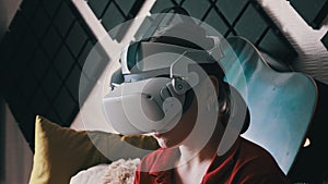 Young Woman in VR Helmet Sitting on Sofa and Communicating in Virtual World