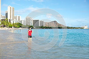 Young woman wading knee deep along Waikiki beach, Hawaii