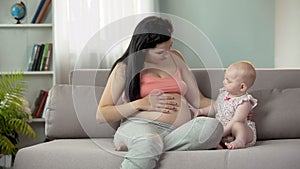 Young woman waiting for birth of baby, cute child touching pregnant belly